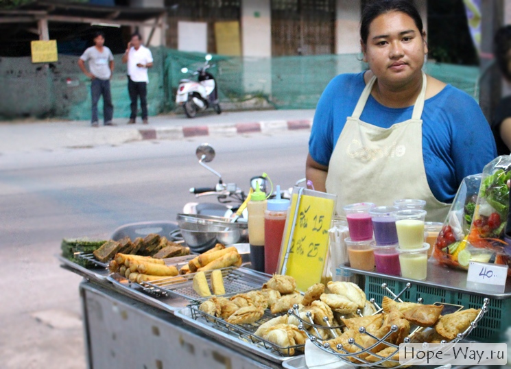 Тайская женщина продает на рынке жареные штуки